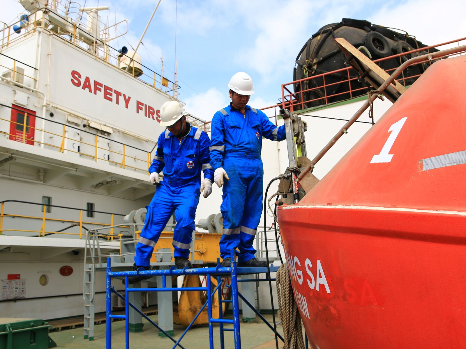 Mermaid technicians servicing a lifeboat on its davits